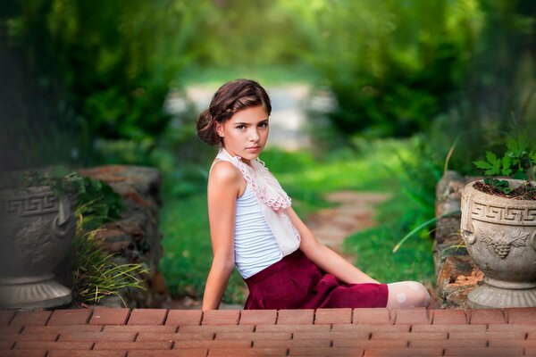 Ragazza sui gradini di mattoni in giardino