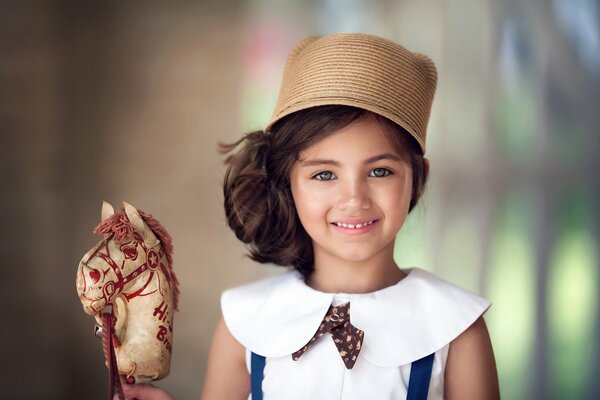 Porträt eines Mädchens mit einem Hut mit einem Spielzeug
