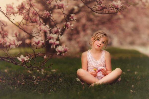 Mädchen mit einem Apfel im Frühling unter den Blumen eines Baumes