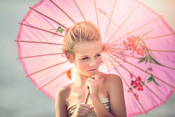 A girl with a pink umbrella smiles