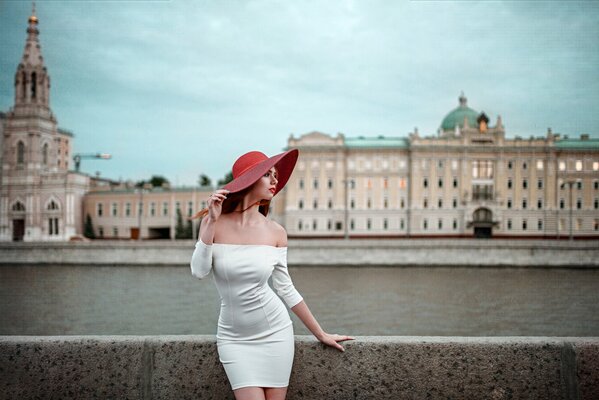 Una chica con un vestido blanco. la chica del sombrero rojo. río. malecón