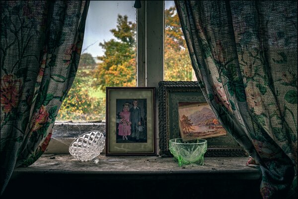 Foto der Fensterbank mit alten Fotos und Vasen auf dem Hintergrund des Herbstlaubs