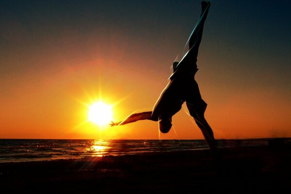 Hombre haciendo gimnasia en la costa al atardecer