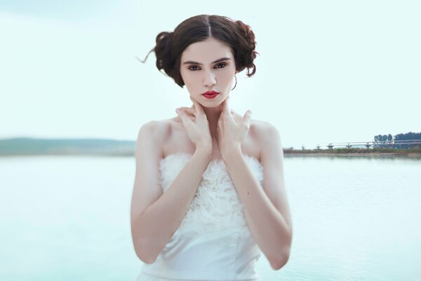 Chica en vestido blanco en la orilla del río