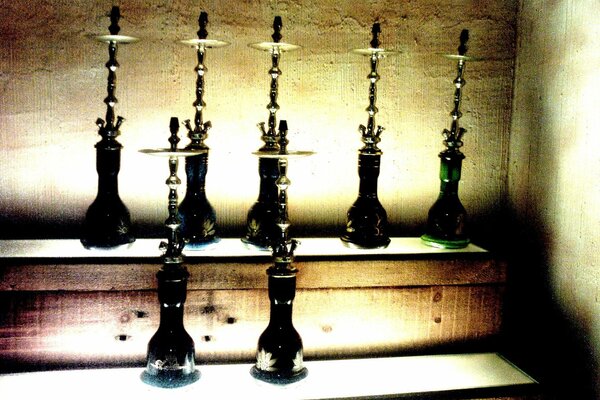 Lots of hookahs on shelves in a dark room