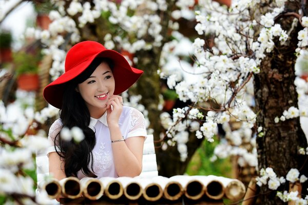 Asian woman in a hat under a flowering tree