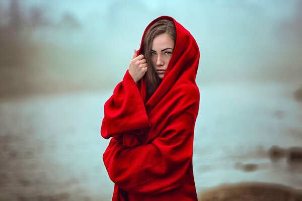 Beautiful girl in a red stole in the fog