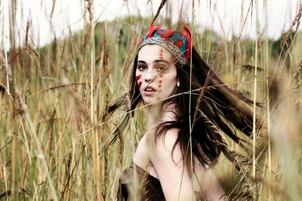 A girl in a field among grass and spikelets in the style of an Indian