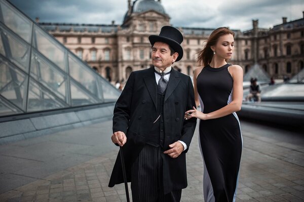 An interesting couple: an aged man and a young girl, walking down the street in Paris