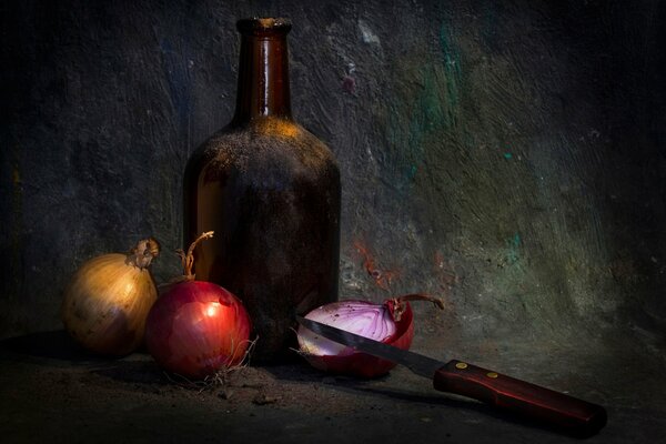 Cebolla y cuchillo al lado de la botella