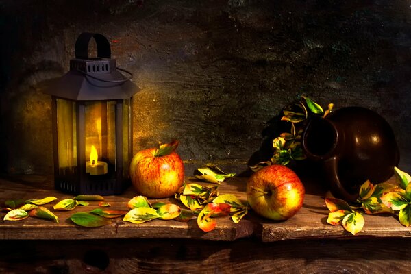 Les pommes sont réchauffées par la lueur d une lanterne près d une cruche