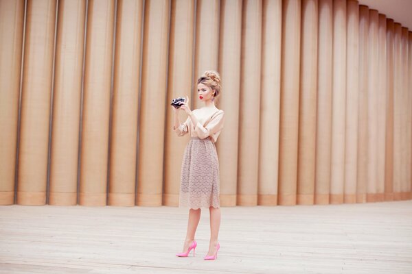 A girl with a camera in a dress and pink shoes