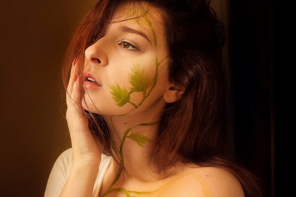 La chica en el perfil con un patrón en la cara en forma de una planta trepadora