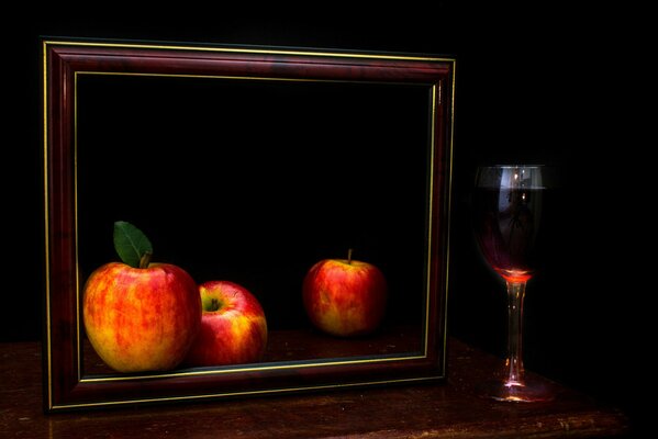Dunkles Stillleben mit Äpfeln und einem Glas Wein