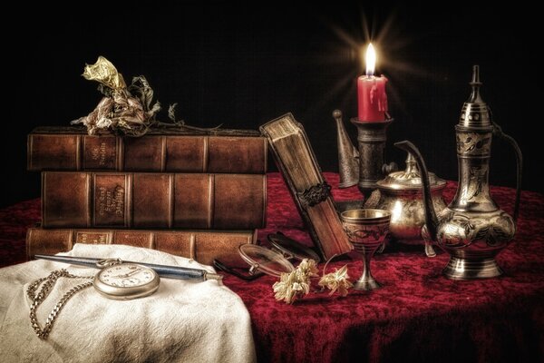 Still life of a table with clocks, dishes and books by candlelight