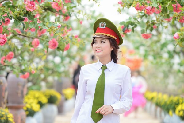 Ragazza in berretto verde cammina nel parco tra gli alberi in fiore