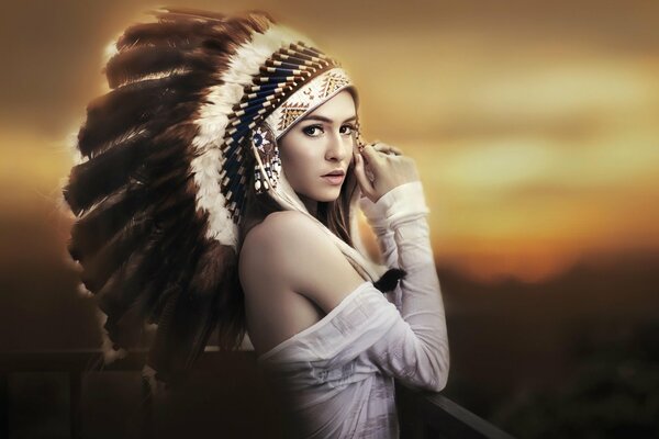 Dziewczyna w białych ubraniach i indiańskich piórach na głowie
