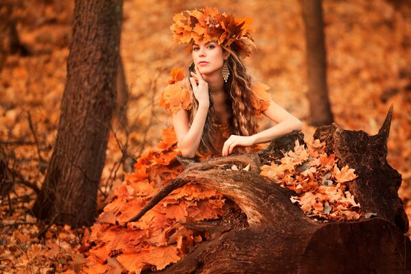 A girl in a dress made of autumn leaves