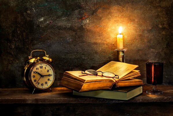 Night is the best time for a book. Alarm clock and candle