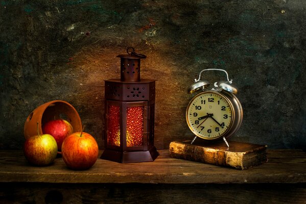 A burning lantern with apples on the table