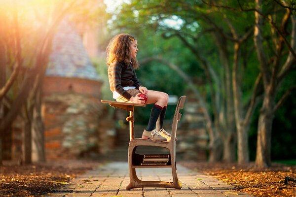 A girl is sitting on a desk outside