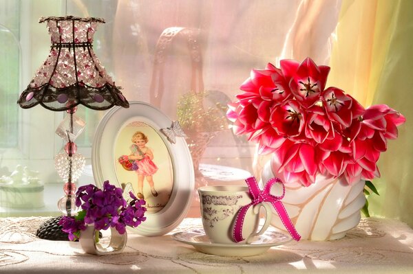 Antique lamp, photo frame and tulips in a vase on the table