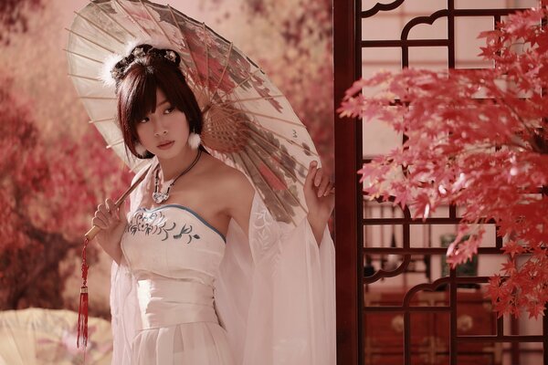 Asiatische Frau im weißen Kleid und Regenschirm im Park