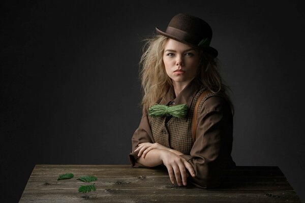 A stylish girl in a hat is sitting at a wooden table
