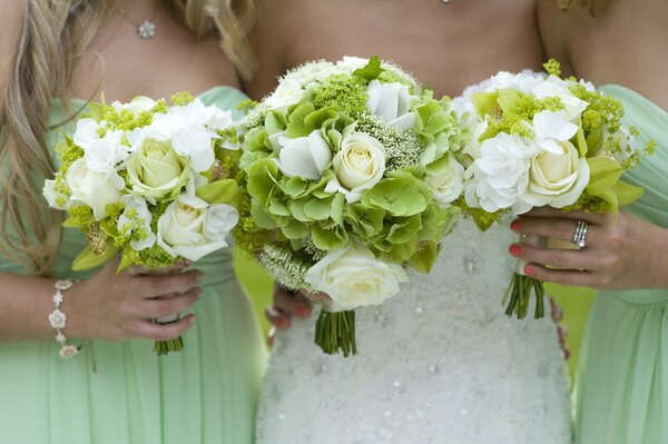 The bride and her girlfriends are holding white and green bouquets