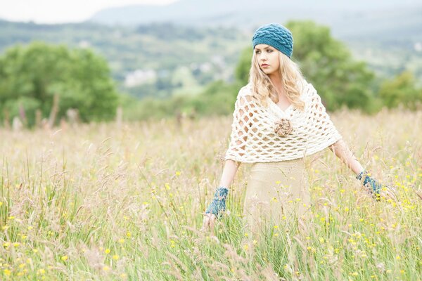 Modische Mädchen auf dem Feld mit einem Kleid und einem gestrickten Baskenmütze auf dem Kopf