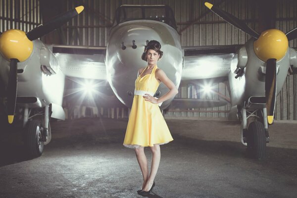 A girl in a yellow dress on the background of an airplane