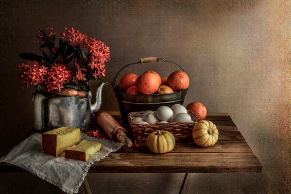 Still life flowers in a teapot, bread, oranges and pumpkins