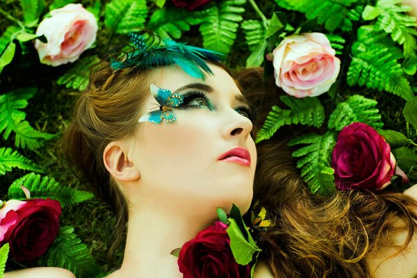 Mädchen im Make-up mit Schmetterlingen und Rosen