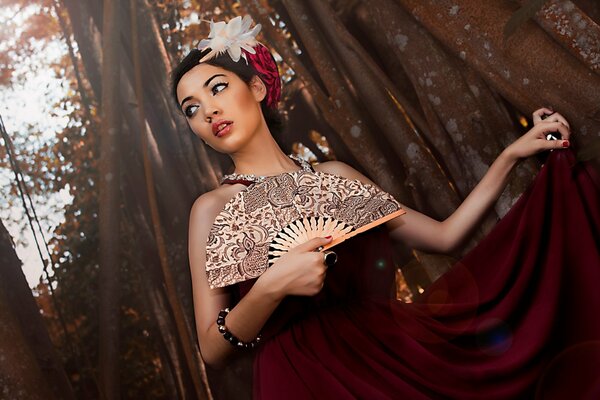 Port ret of a girl in a dark red dress with a fan in her hand