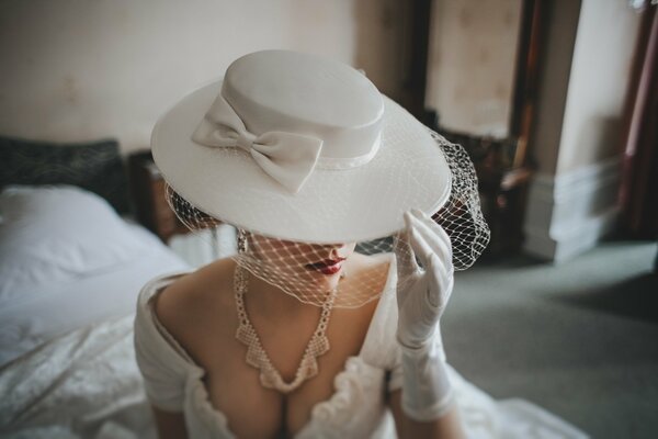 Immagine della sposa: abito bianco, cappello, guanti, collana