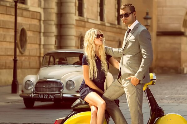 Estate a Copenaghen, coppia in abiti alla moda con un ciclomotore giallo e un auto d epoca