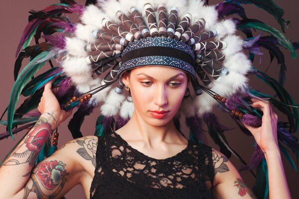 Portrait of a girl with tattoos and wearing an American Indian headdress