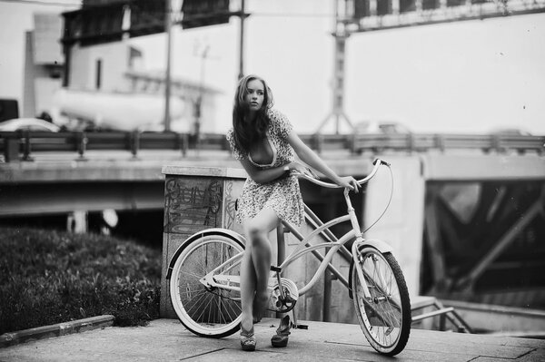 Photo dans un style rétro, une fille en robe courte avec un vélo sur le fond d un échangeur routier
