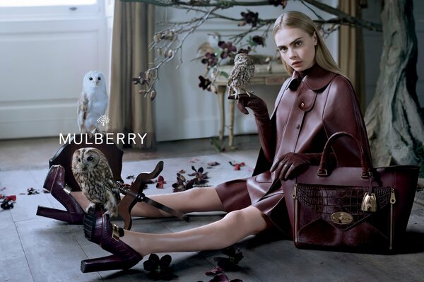 Stylish girl with owls in a leather raincoat and with a big bag