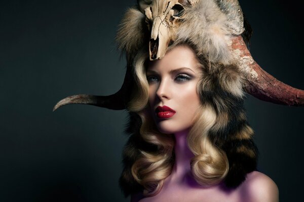 Portrait of a girl with red lips with an animal skull on her head