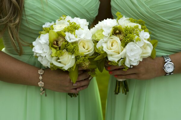 Zwei Mädchen in identischen grünlichen Kleidern und mit Blumensträußen