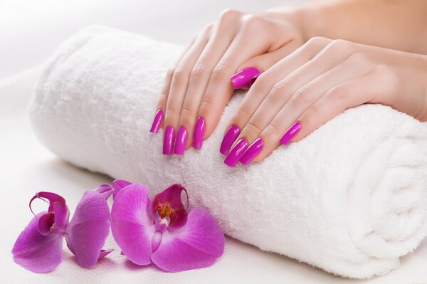 Fresh manicure in the color of an orchid on a white towel