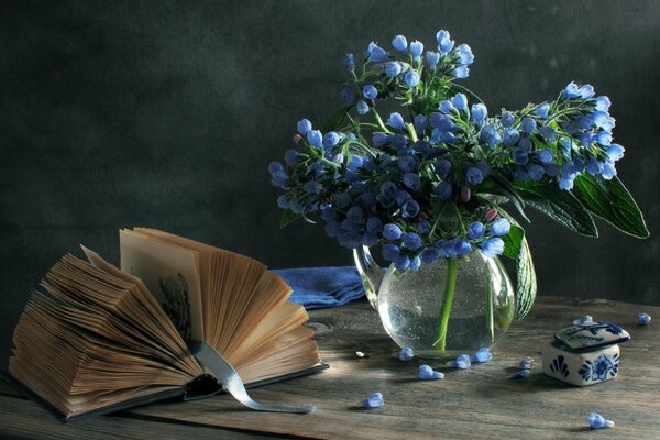 An open book on the table next to a vase of flowers