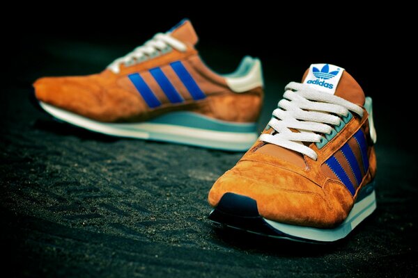 Orange adidas sneakers with blue stripes