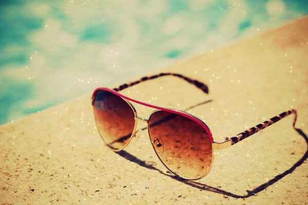 Lunettes élégantes se trouvent sur un fond de sable