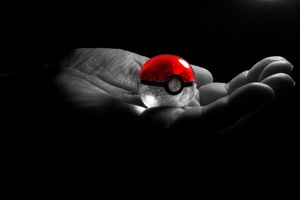 Red pokeball on the palm of your hand on a black background