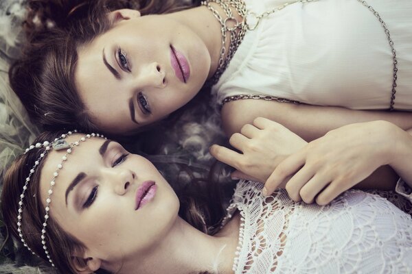 Two girls in jewelry are lying on the ground