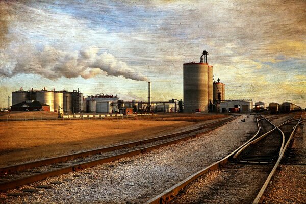 Immagine della ferrovia, della fabbrica, del fumo e del cielo