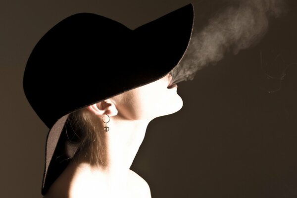 A beautiful girl in a hat with a cigar