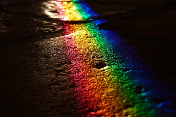 Resplandor del arco iris en la superficie de la carretera por la noche